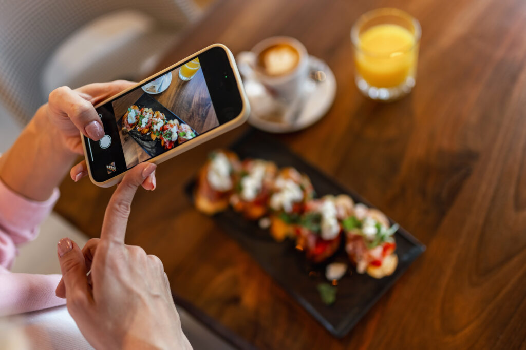 A women taking a photo of her food in a restaurant to post on social media